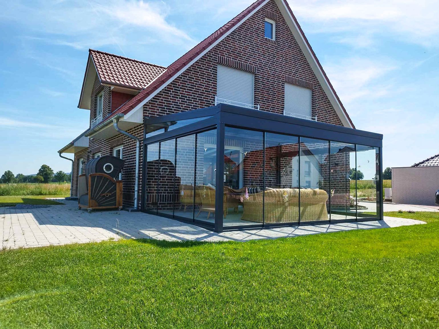 Wintergarten mit Glasschiebewänden an einem Klinkerhaus